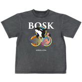 The BOSK World Tee is a classic fit, heavy-weight faded black t-shirt featuring bold white "BOSK" lettering above cartoon orca, elephant, and flamingo in colorful circles and "AFRICA USA" underneath for a casual, worn look.
